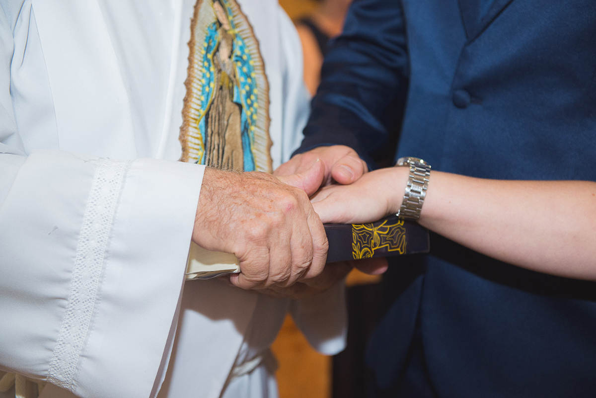 Noivos com a mão na bíblia durante a cerimônia de casamento. Foto por Marco Moscarelli Fotografo.