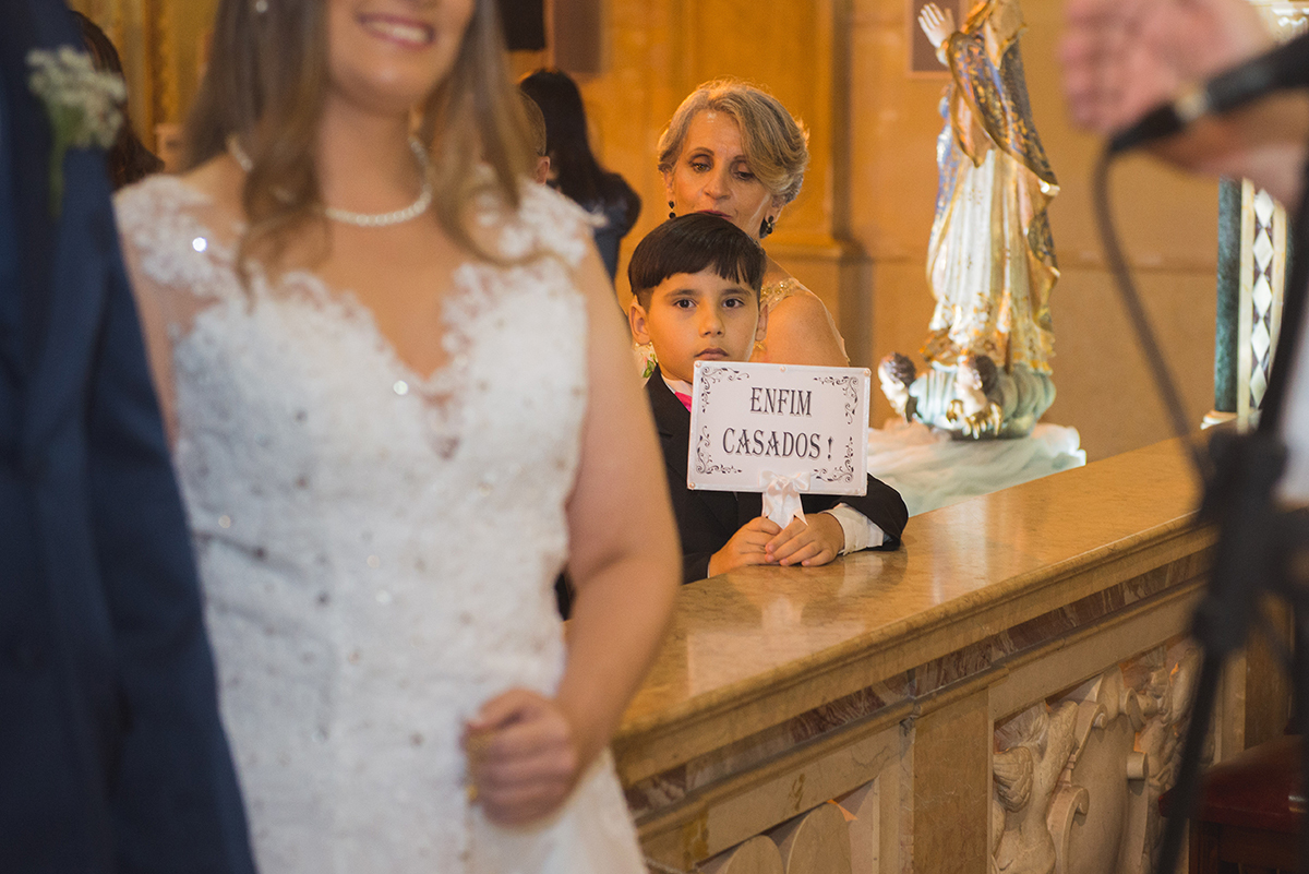 Pagem acompanhando o casamento do altar com a plaquinha de enfim casados. Foto por Marco Moscarelli Fotografo.