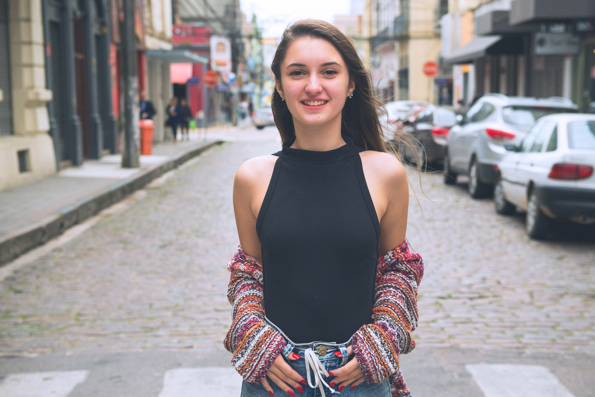 Debutante rindo divertidamente e fazendo diversas poses no meio da rua durante seu ensaio fotográfico de 15 anos. Foto por Marco Moscarelli Fotografo.