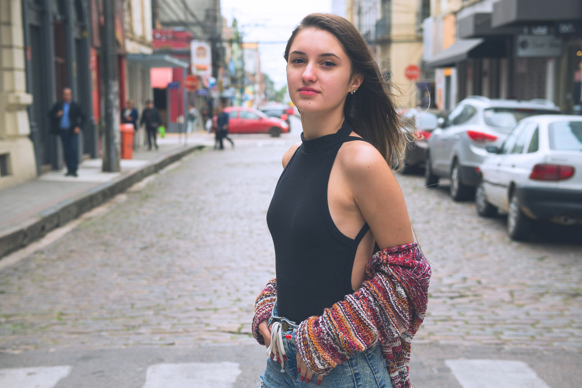 Debutante rindo divertidamente e fazendo diversas poses no meio da rua durante seu ensaio fotográfico de 15 anos. Foto por Marco Moscarelli Fotografo.