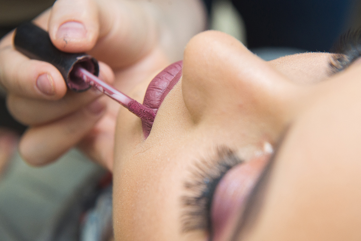 Maquiadora colocando baton  durante a maquiagem da debutante. Foto por Marco Moscarelli Fotografo.
