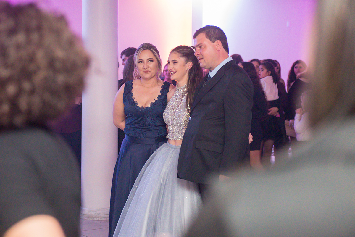 Aniversariante abraçada nos seus pais durante as homenagens na festa de 15 anos. Foto por Marco Moscarelli Fotografo.