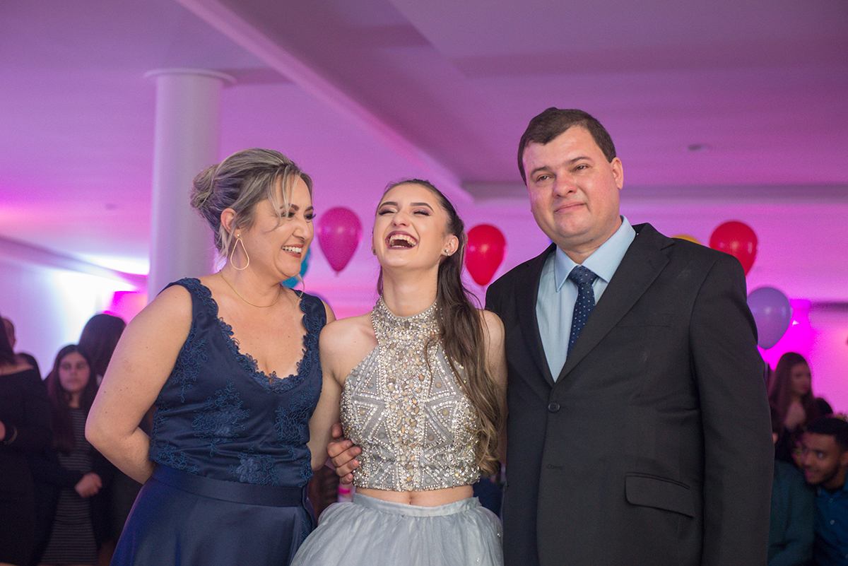 Aniversariante abraçada nos seus pais durante as homenagens na festa de 15 anos. Foto por Marco Moscarelli Fotografo.