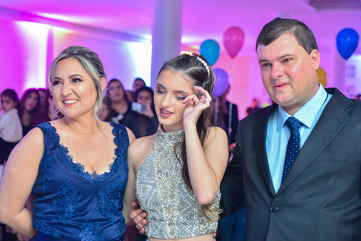 Aniversariante abraçada nos seus pais durante as homenagens na festa de 15 anos. Foto por Marco Moscarelli Fotografo.