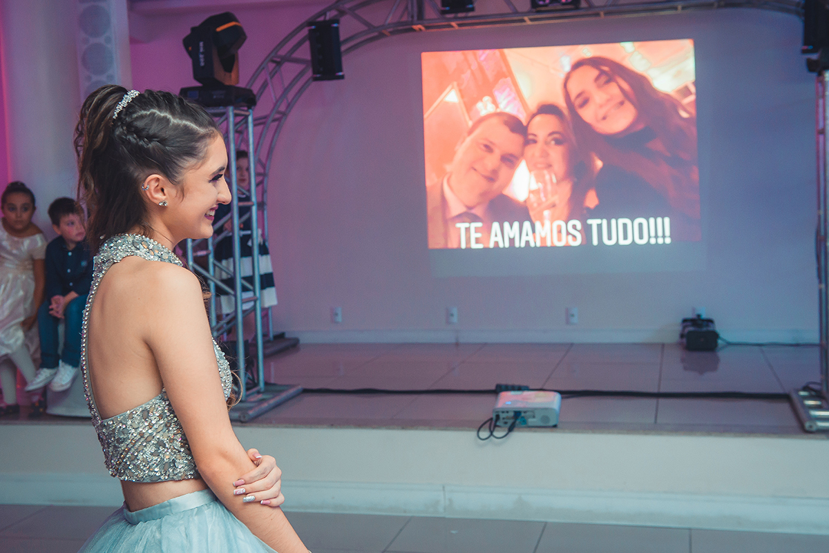 Aniversariante emocionada olhando os videos no seu aniversário de 15 anos. Foto por Marco Moscarelli Fotografo.