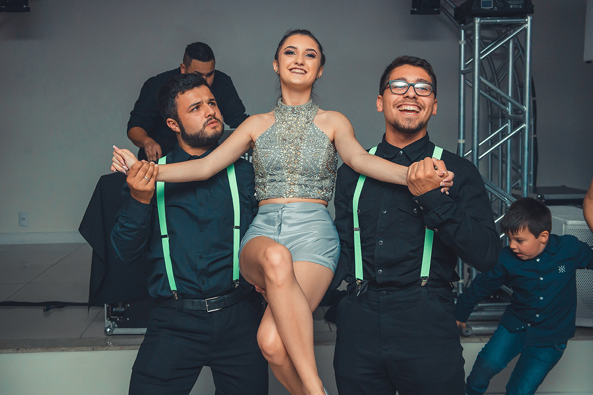 Debutante abrindo a pista de dança sendo carregada por dois convidados durante o seu aniversário de 15 anos. Foto por Marco Moscarelli 