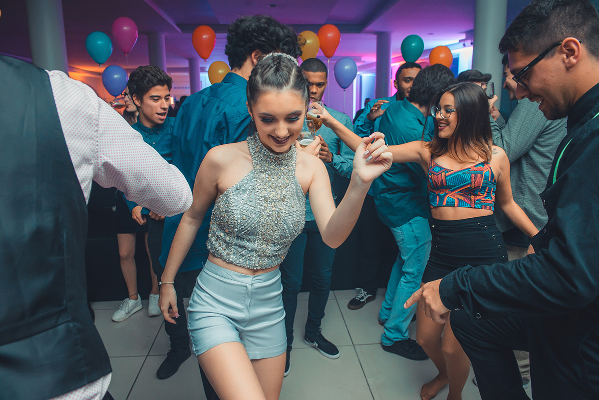 Aniversariante dançando alegremente com seus convidados durante a sua festa de 15 anos. Foto por Marco Moscarelli Fotografo.