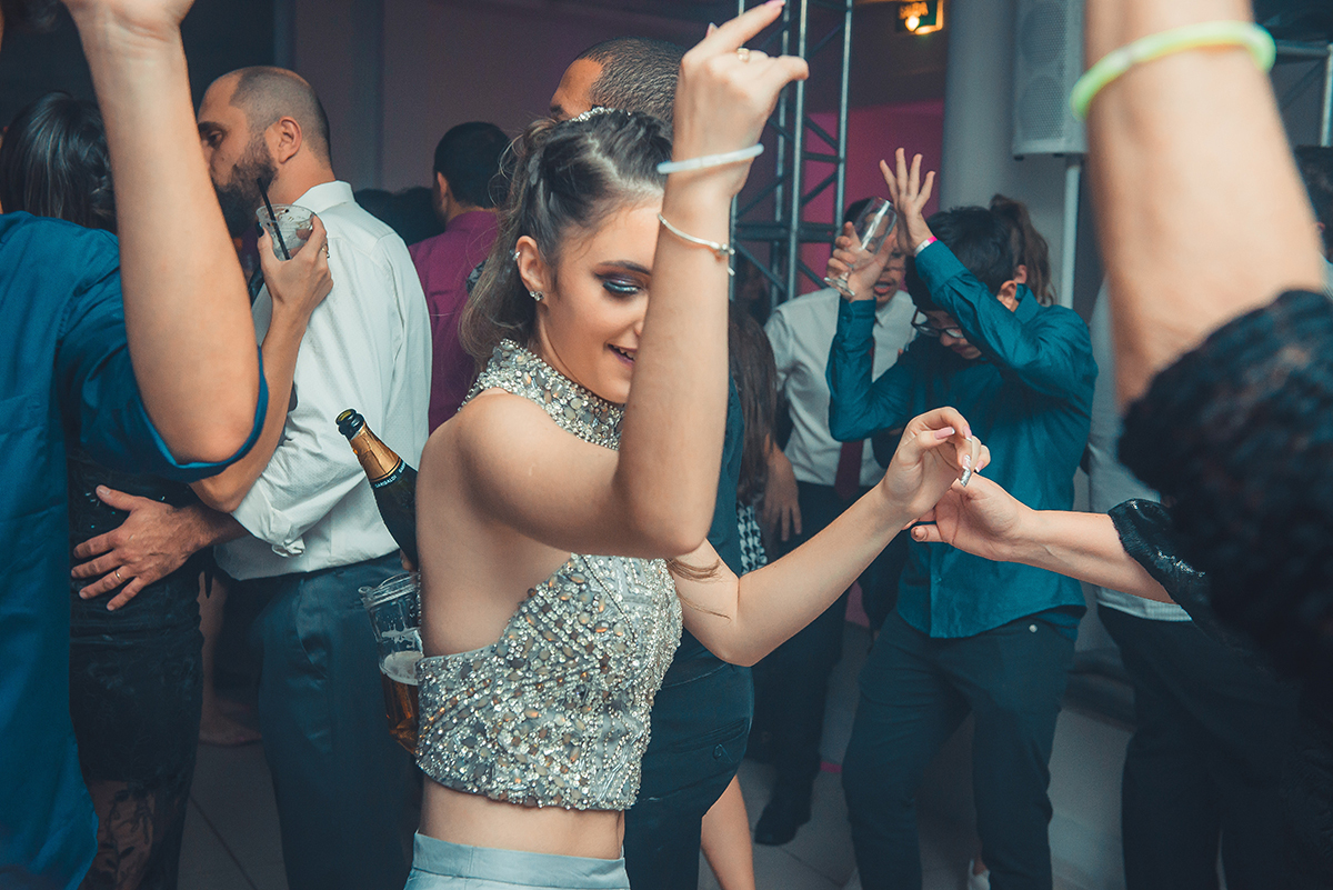 Aniversariante dançando alegremente com seus convidados durante a sua festa de 15 anos. Foto por Marco Moscarelli Fotografo.