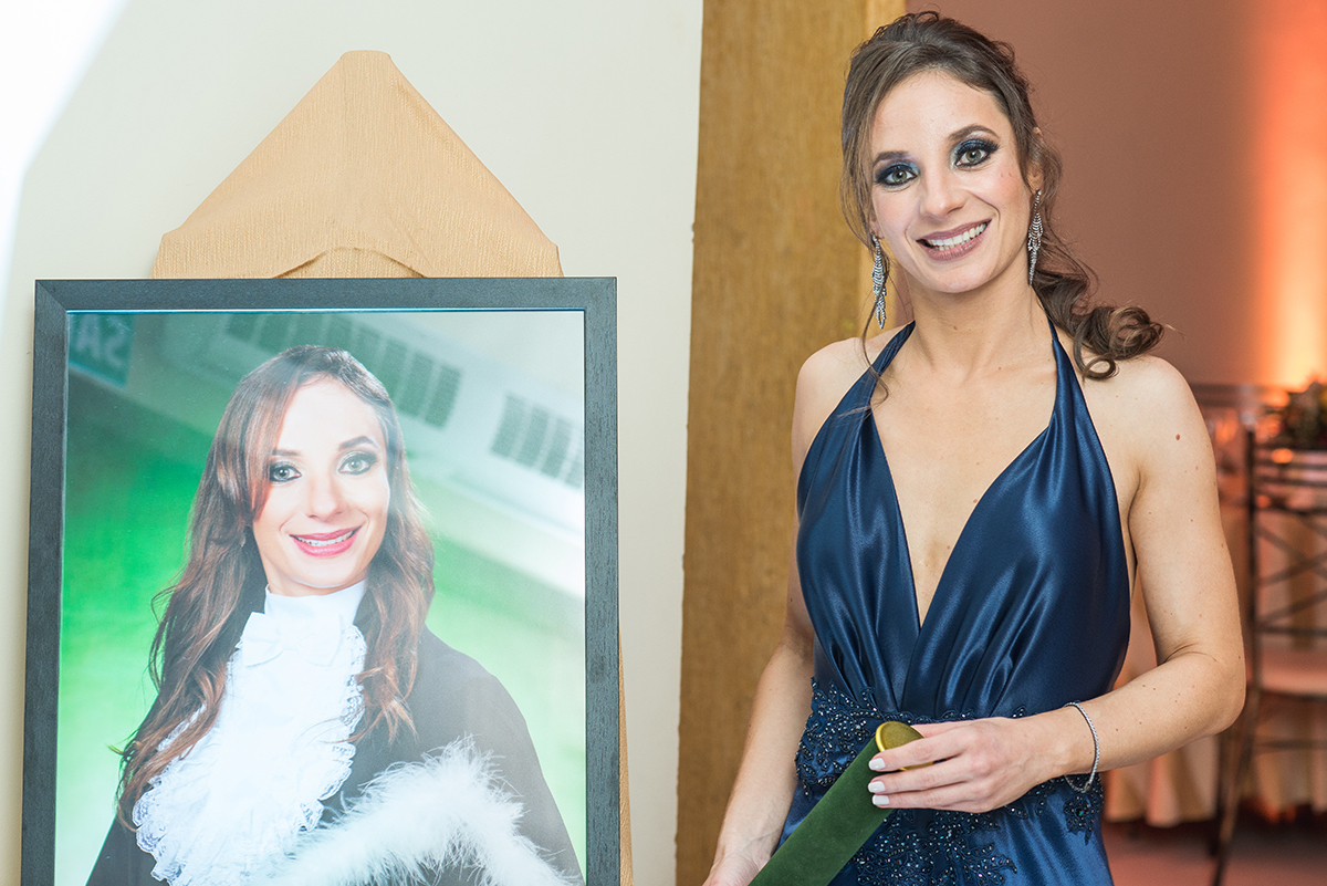 Formanda posando para fotos ao lado do seu quadro de formatura em medicina em Pelotas. foto por Marco Moscarelli