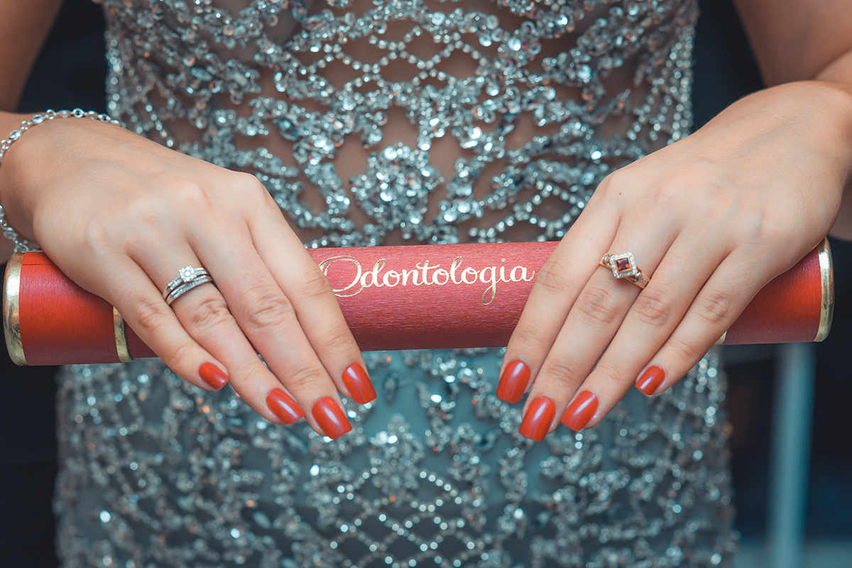 Foto linda  da formanda segurando seu canudo de formatura e mostrando seu anel de formatura  durante a sua recepção de formatura. Foto por Marco Moscarelli Fotografo.
