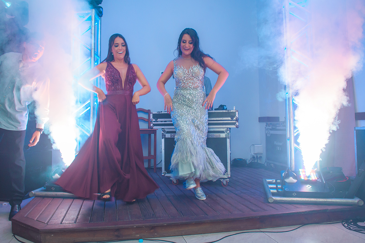 Formanda dançando no palco em em meio a  colunas de fumaça durante a sua recepção de formatura em odontologia em pelotas. Foto por Marco Moscarelli Fotografo.