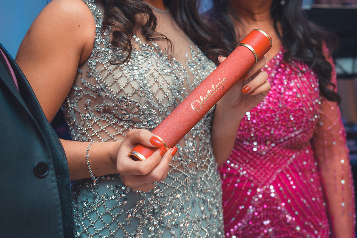 Fotografia em detalhe do canudo de formatura nas mãos da formanda durante a recepção de formatura. Foto por Marco Moscarelli Fotografo.