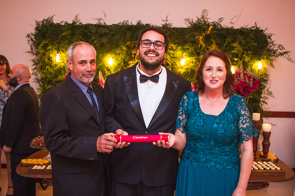 Fotografia do formando com seus pais durante a recepção de formatura em odontologia. Foto por Marco Moscarelli Fotografo.