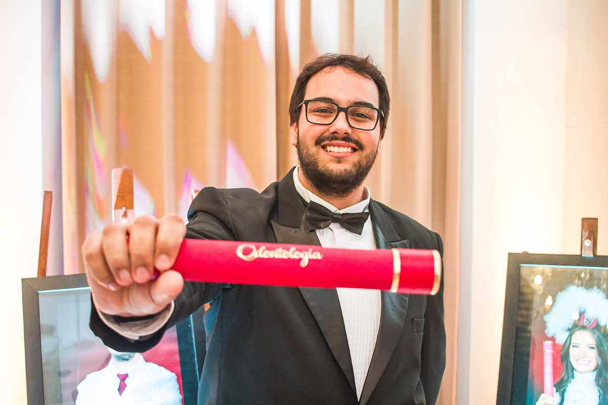 Formando posando para foto descontraida com seu canudo de formatura. Foto Por Marco Moscarelli Fotografo.