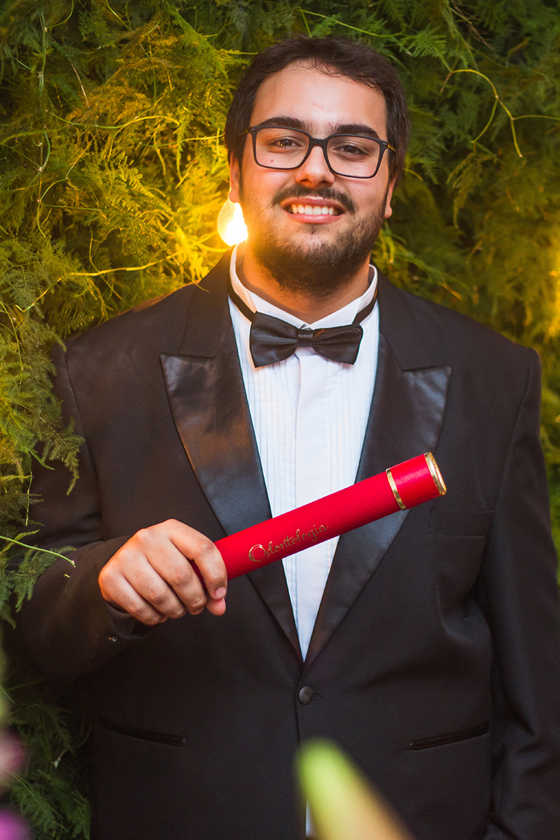 Formando posando para foto descontraida com seu canudo de formatura. Foto Por Marco Moscarelli Fotografo.