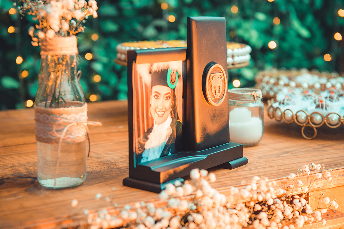 Detalhe da decoração da mesa da formanda no dia da sua formatura com o quadrinho de formatura em primeiro plano. foto por Marco Moscarelli Fotografo.