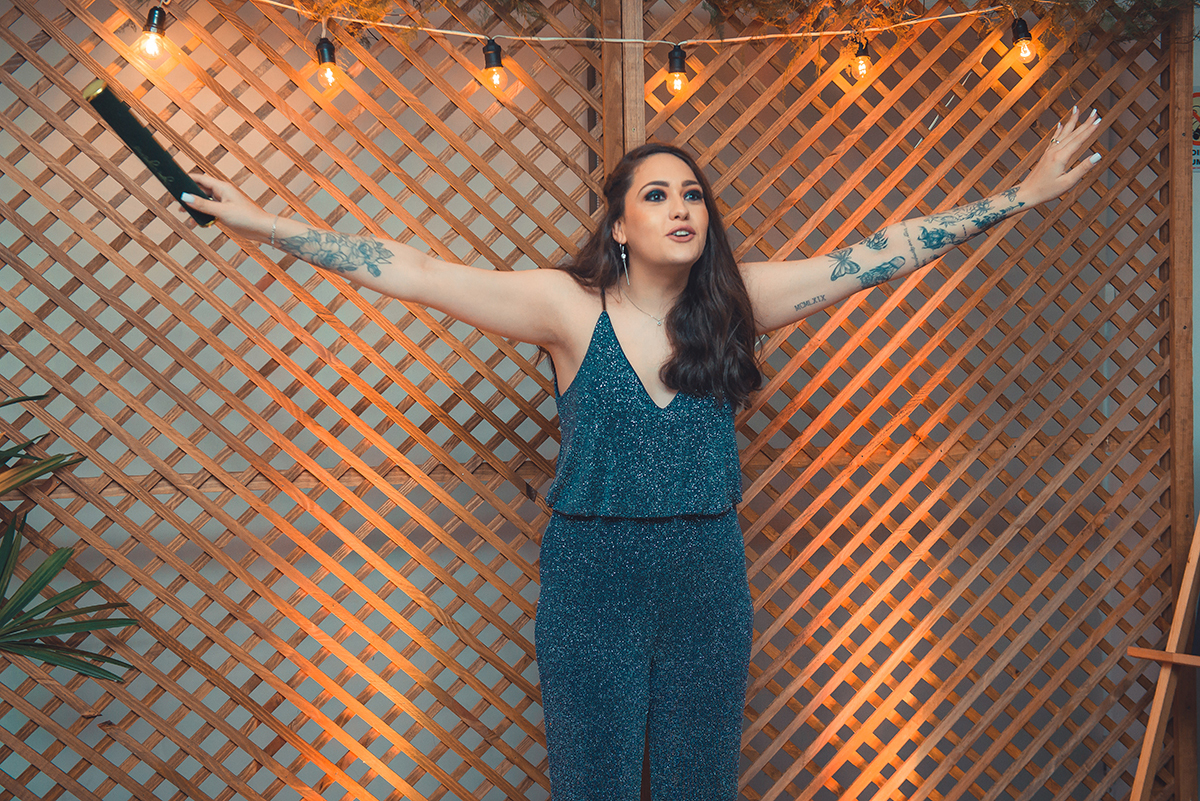 Formanda em momento alegre com os braços abertos convidando a todos para se divertir em sua recepção de formatura. Foto por Marco Moscarelli Fotografo.
