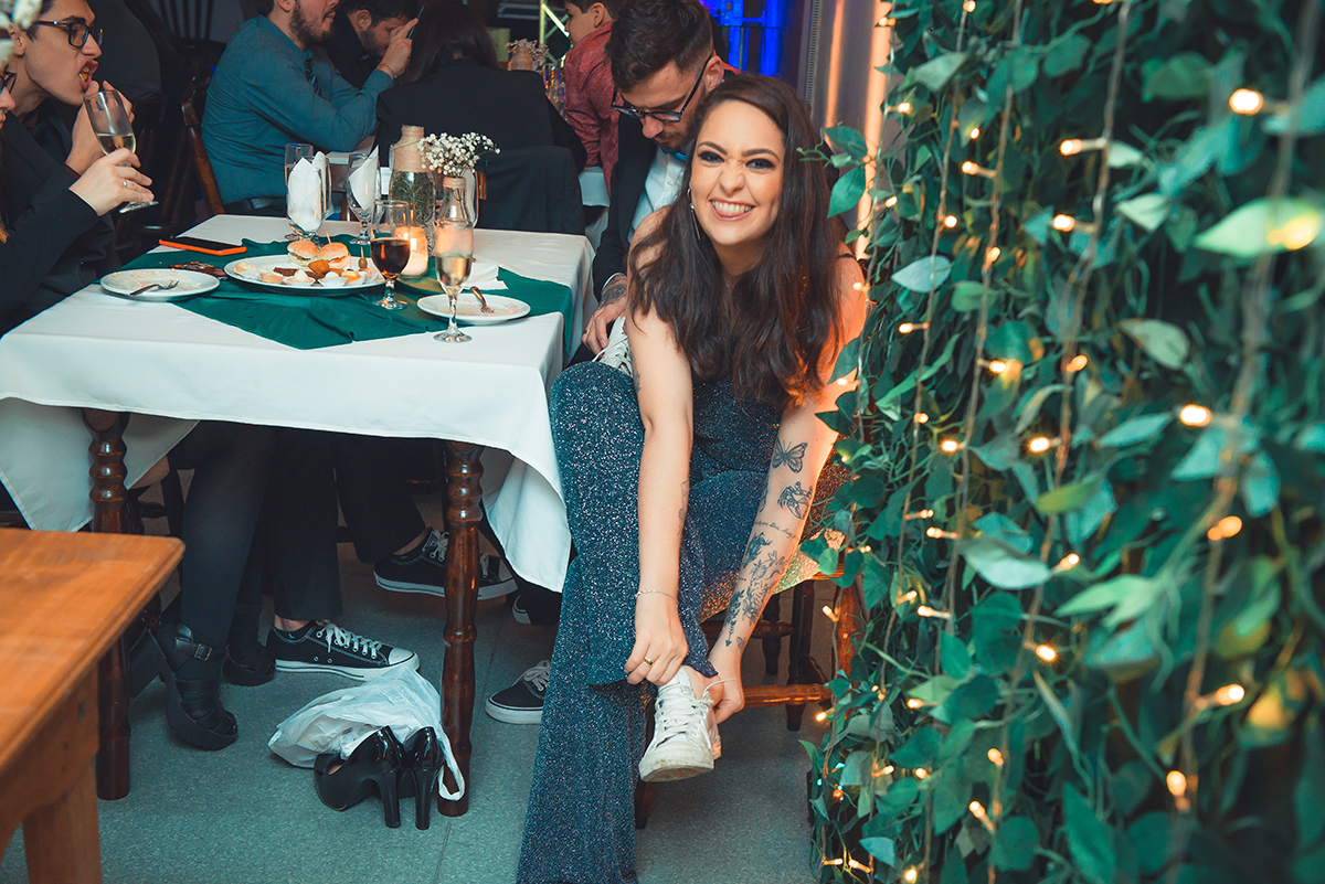 Foto de momento descontraído da formanda trocando seu sapato de salto por um tênis para aproveitar sua recepção de formatura. Foto por Marco Moscarelli Fotografo. 