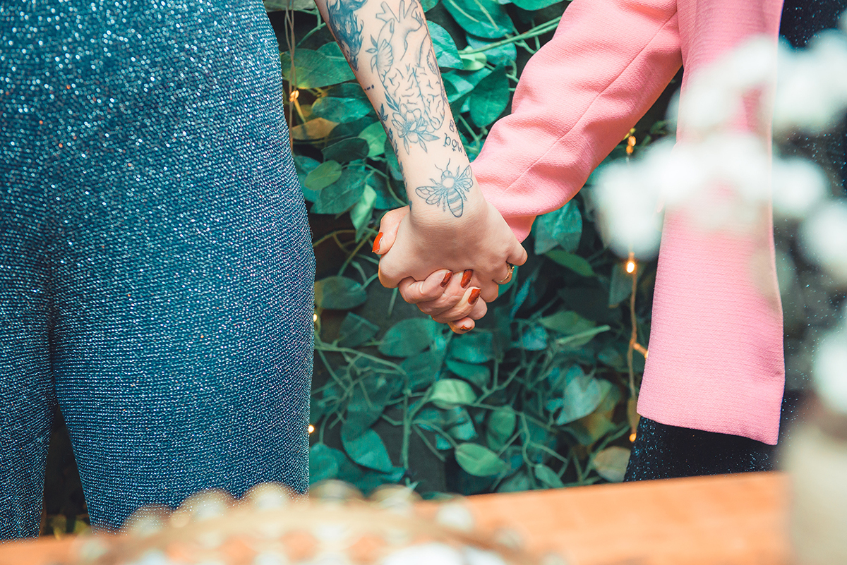 Fotografia em detalhe da formanda de mãos dadas com sua avó durante o discurso na recepção de formatura. Foto por Marco Moscarelli Fotografo.