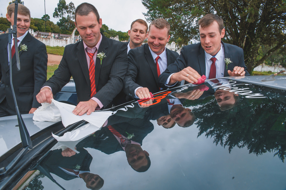 Padrinhos decorando o carro dos noivos após o casamento.  Foto por Marco Moscarelli Fotografo Pelotas.