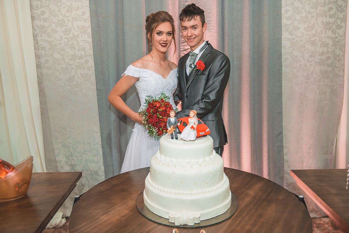noivos posando para retrato juntos a mesa do bolo. Foto por Marco Moscarelli Fotografo Pelotas.