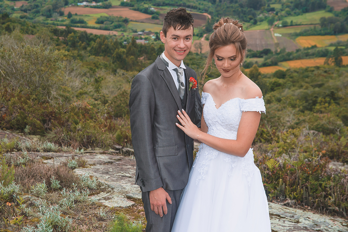Noivos posando para foto de ensaio pós casamento com um lindo vale da colonia de pelotas ao fundo.  Foto por Marco Moscarelli Fotografo Pelotas.