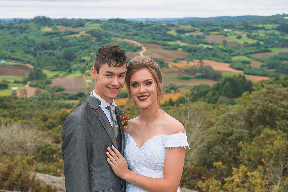 Noivos posando para foto de ensaio pós casamento com um lindo vale da colonia de pelotas ao fundo.  Foto por Marco Moscarelli Fotografo Pelotas.