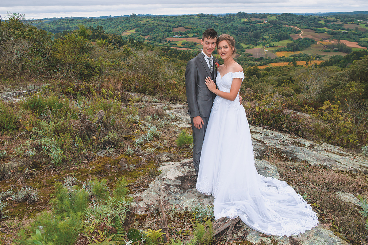 Noivos posando para foto de ensaio pós casamento com um lindo vale da colonia de pelotas ao fundo.  Foto por Marco Moscarelli Fotografo Pelotas.