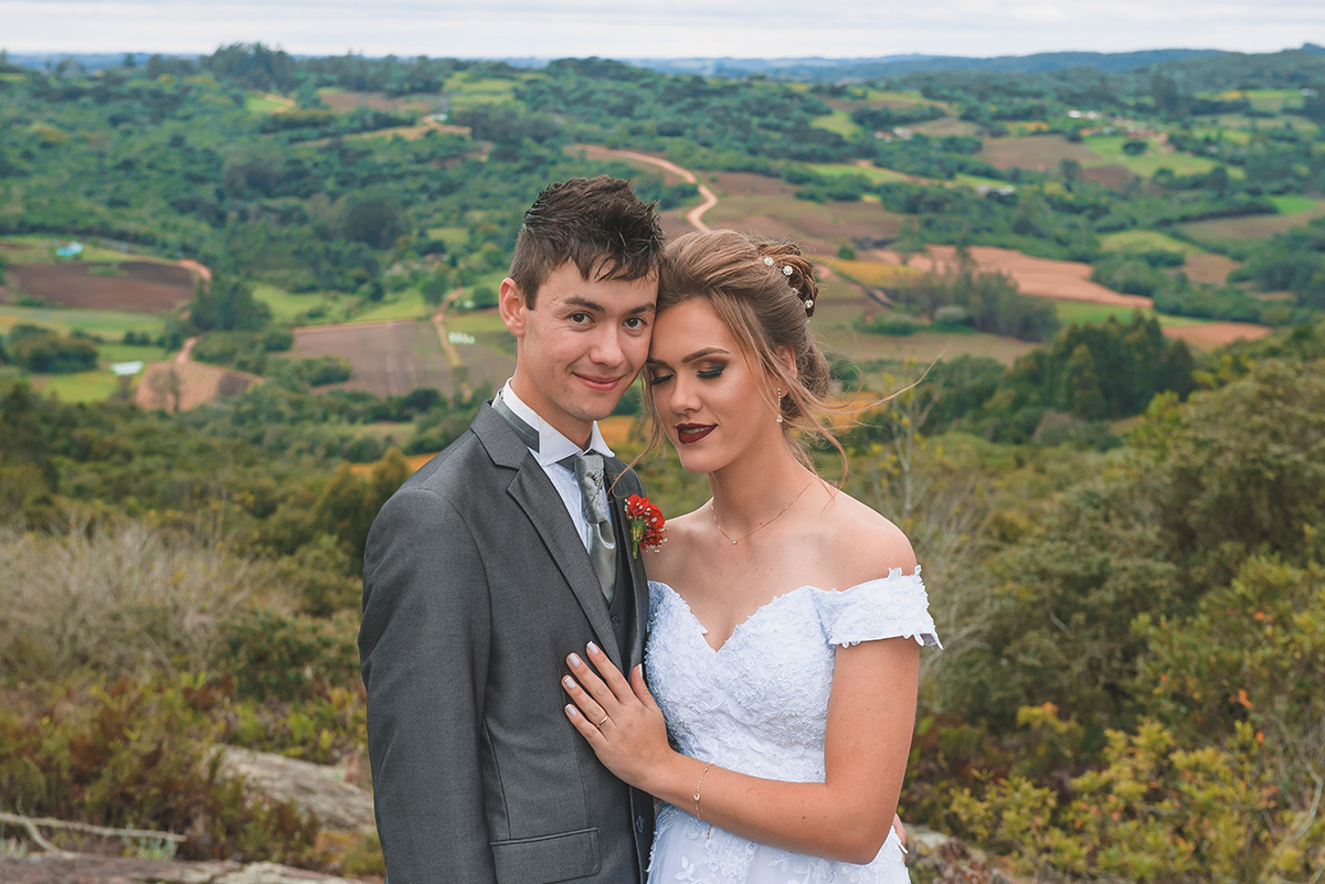Noivos posando para foto de ensaio pós casamento com um lindo vale da colonia de pelotas ao fundo.  Foto por Marco Moscarelli Fotografo Pelotas.