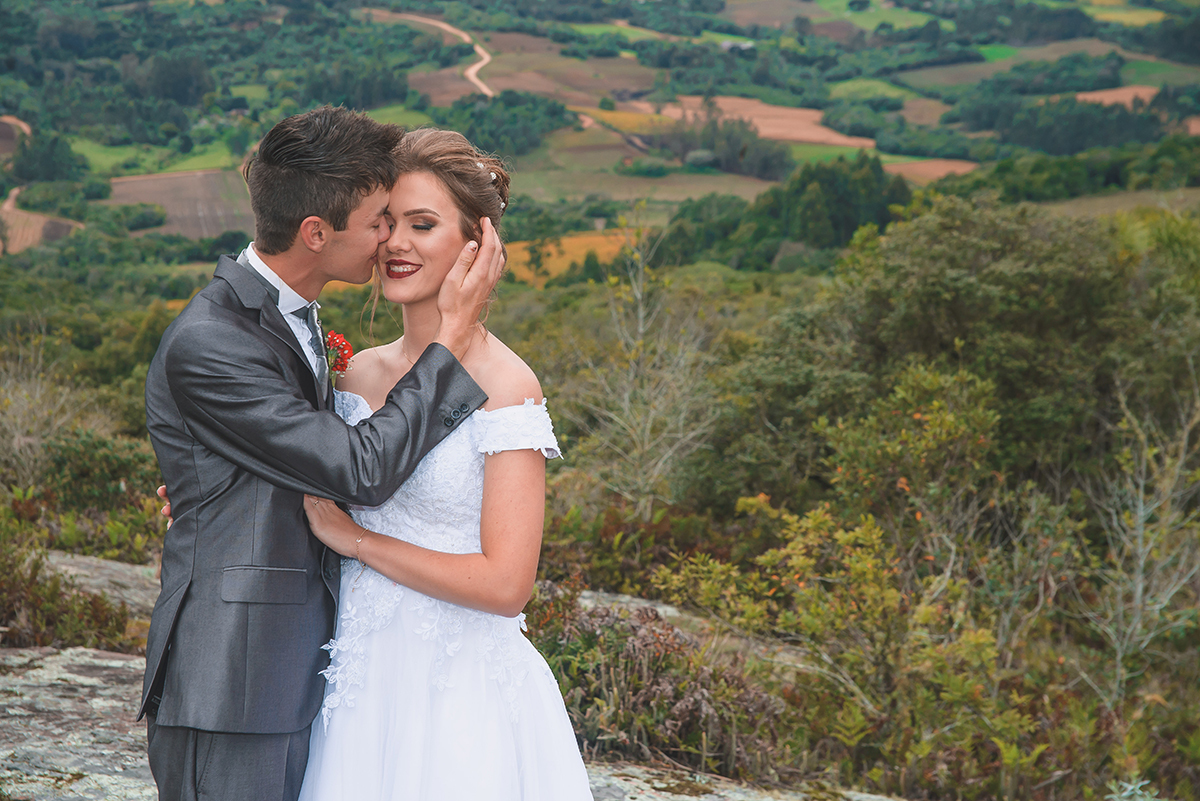 Noivos posando para foto de ensaio pós casamento com um lindo vale da colonia de pelotas ao fundo.  Foto por Marco Moscarelli Fotografo Pelotas.