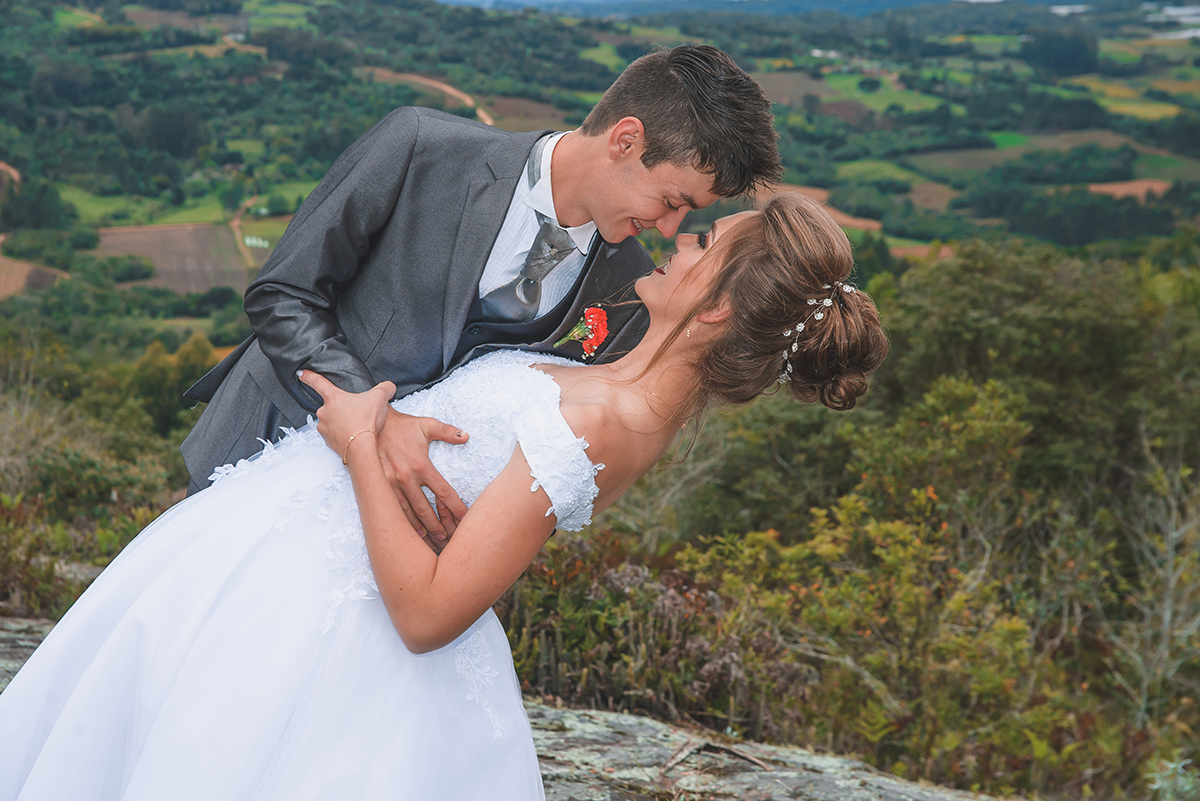 Noivos posando para foto de ensaio pós casamento com um lindo vale da colonia de pelotas ao fundo.  Foto por Marco Moscarelli Fotografo Pelotas.