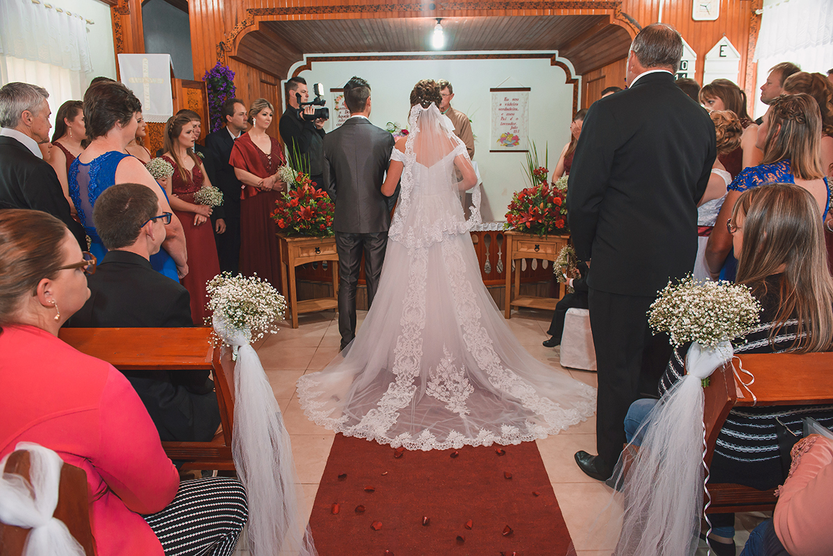 Noivos no altar do casamento foto feita na entrada da igreja com noivos ao fundo. Foto por Marco Moscarelli Fotografo Pelotas.