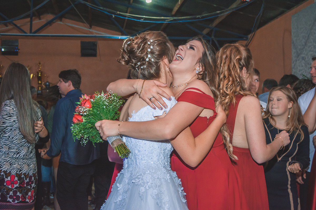 Madrinha que pegou o buque dando um abraço na noiva durante a festa de casamento. Foto por Marco Moscarelli Fotografo Pelotas.