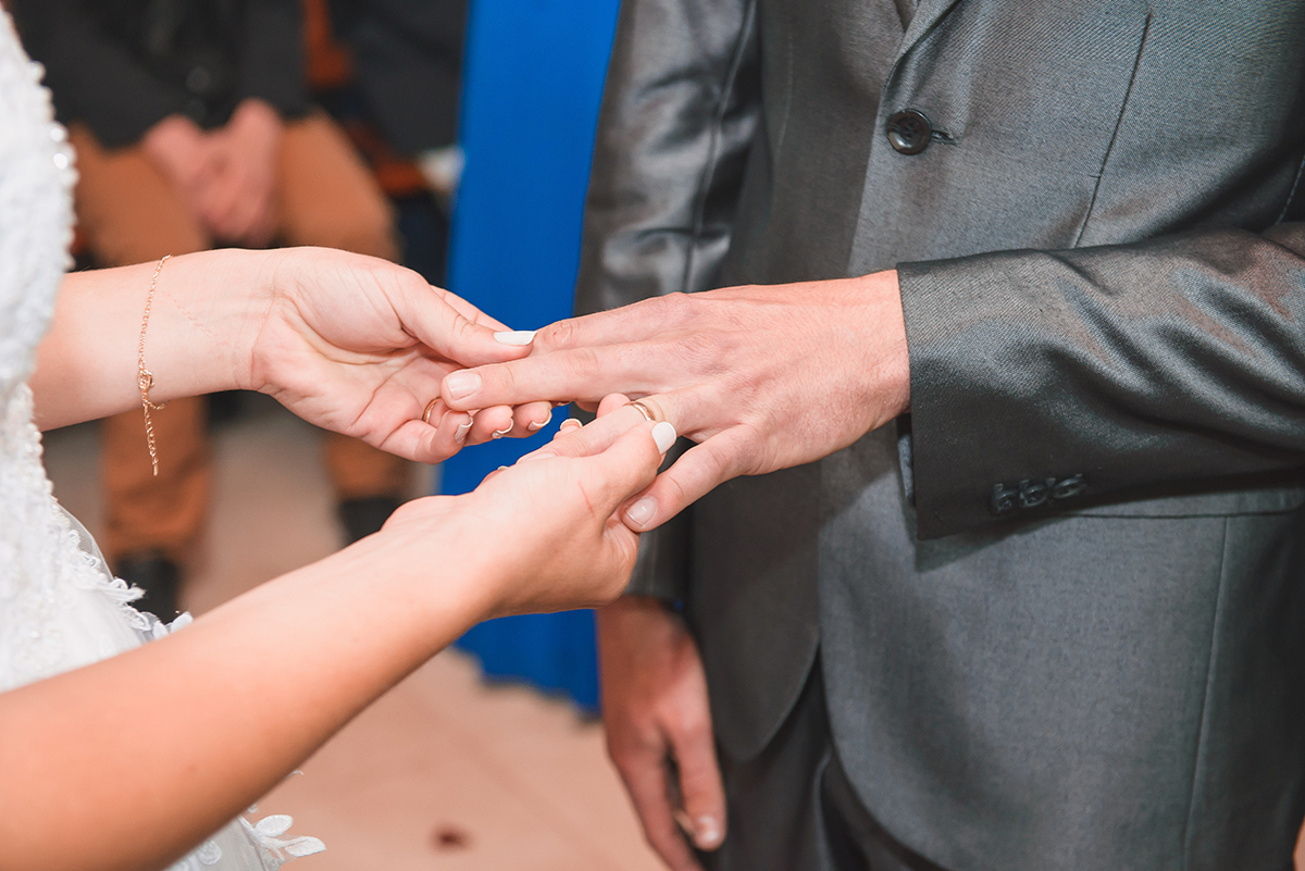 Foto em detalhe do momento da troca de alianças dos noivos durante o casamento. Foto por Marco Moscarelli Fotografo Pelotas.