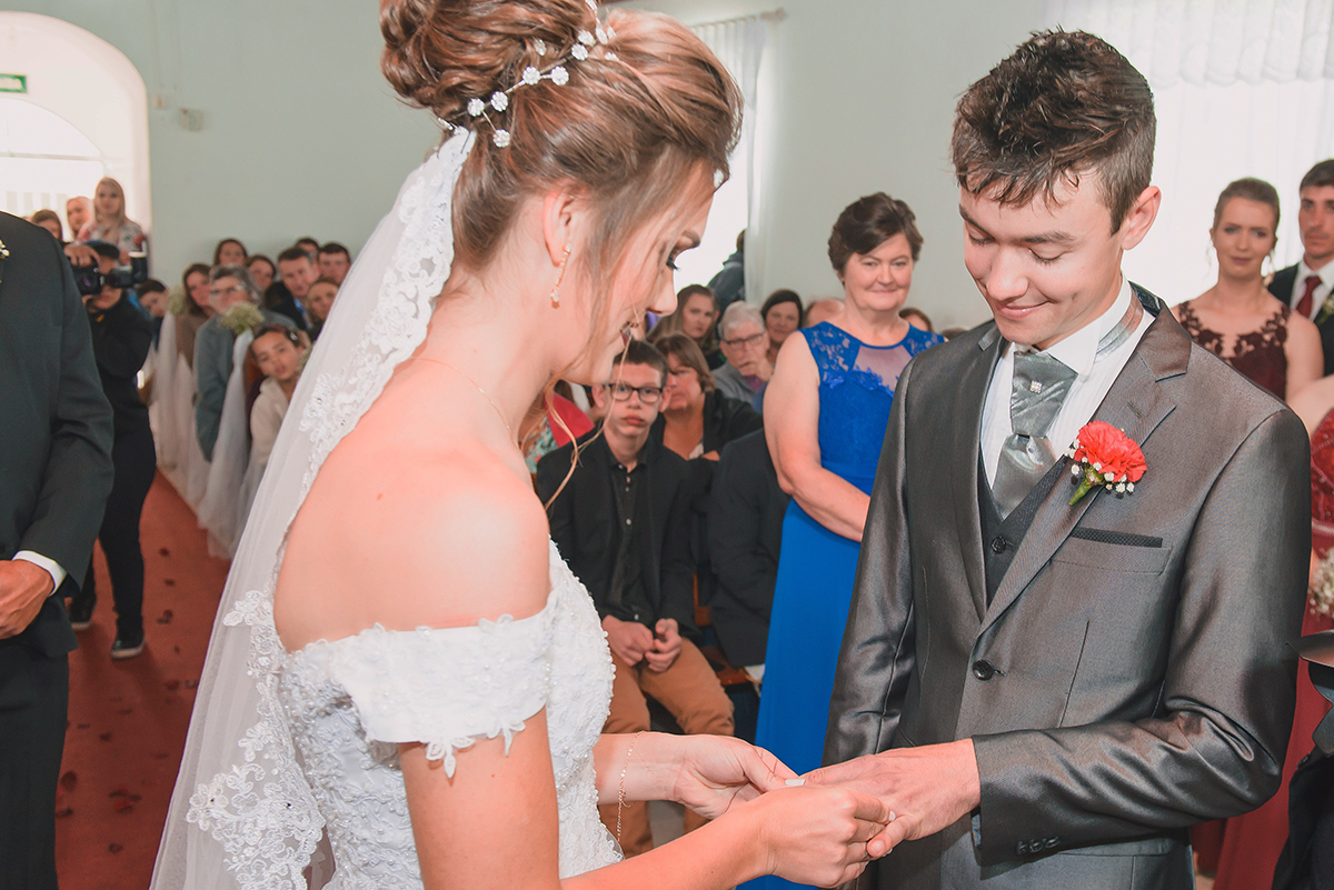 Foto em detalhe do momento da troca de alianças dos noivos durante o casamento. Foto por Marco Moscarelli Fotografo Pelotas.