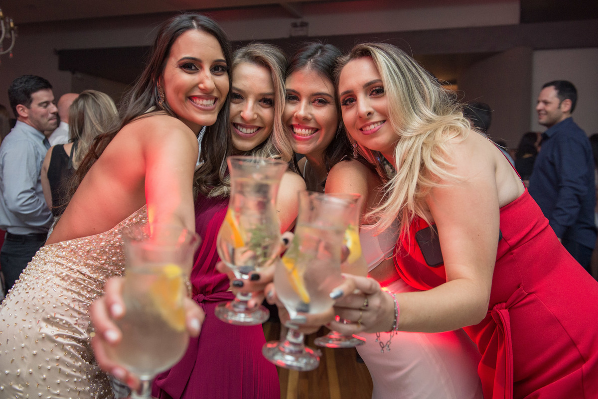 Formanda dançando feliz durante a festa de formatura com suas amigas e brindando. Foto por Marco Moscarelli Fotografo Pelotas.