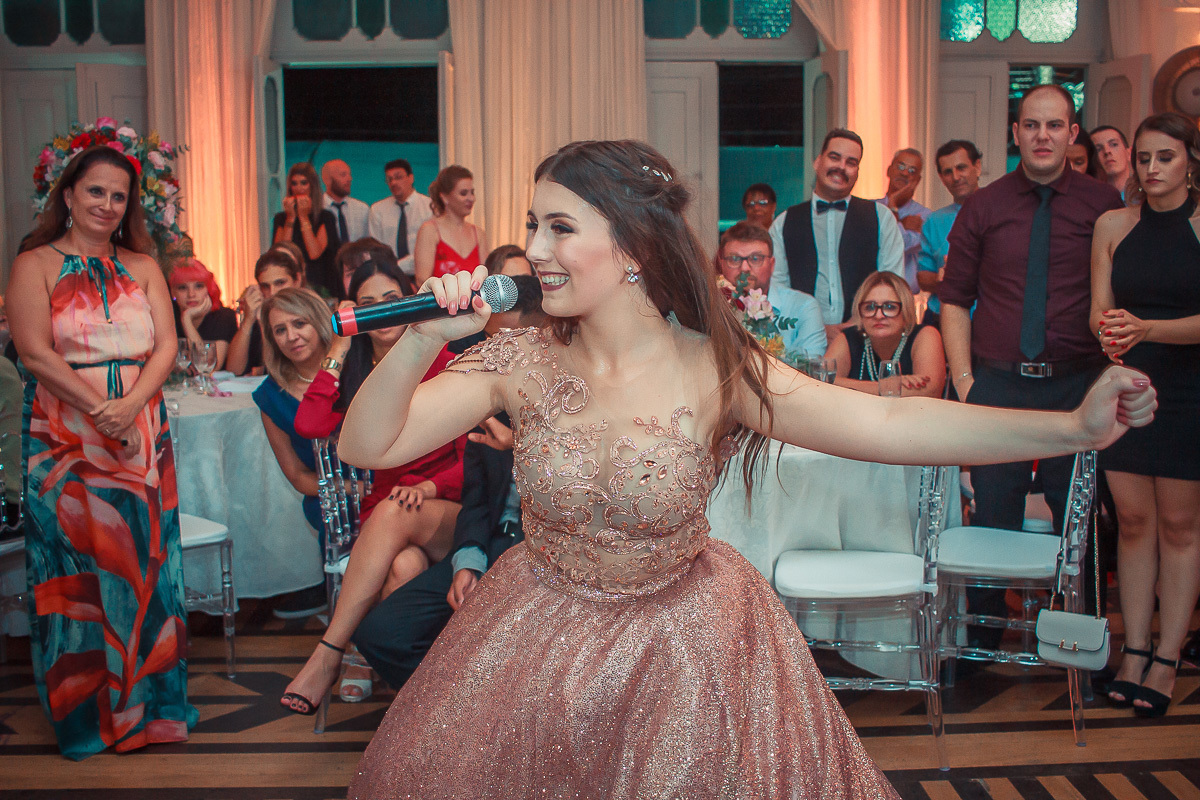 Debutante alegre com o microfone na mão chamando seus convidados para a dança durante a sua festa de 15 anos em jaguarão.  Foto por Marco Moscarelli fotografo Pelotas. 