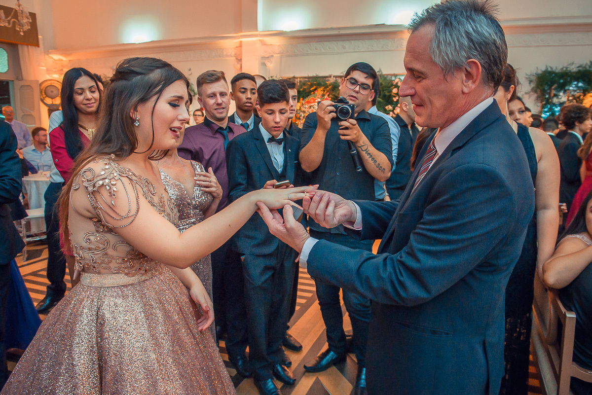 pai da debutante colocando o anel de 15 anos no dedo da aniversariante em sua  festa de 15 anos em jaguarão. Foto por Marco Moscarelli  fotografo pelotas.