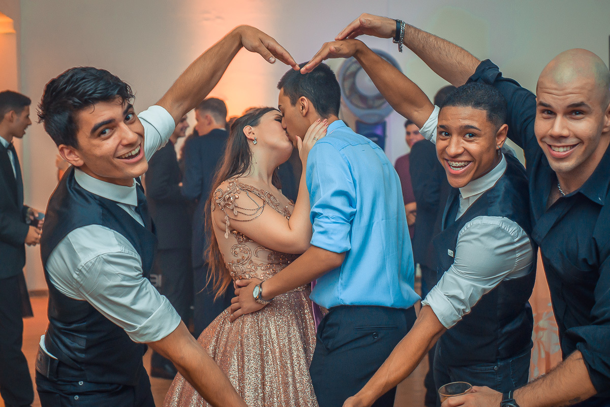 Convidados fazendo um coração com os braços fazendo moldura enquanto a debutante beija o namorado durante a sua festa de 15 anos em jaguarão. Foto por Marco Moscarelli  fotografo pelotas.