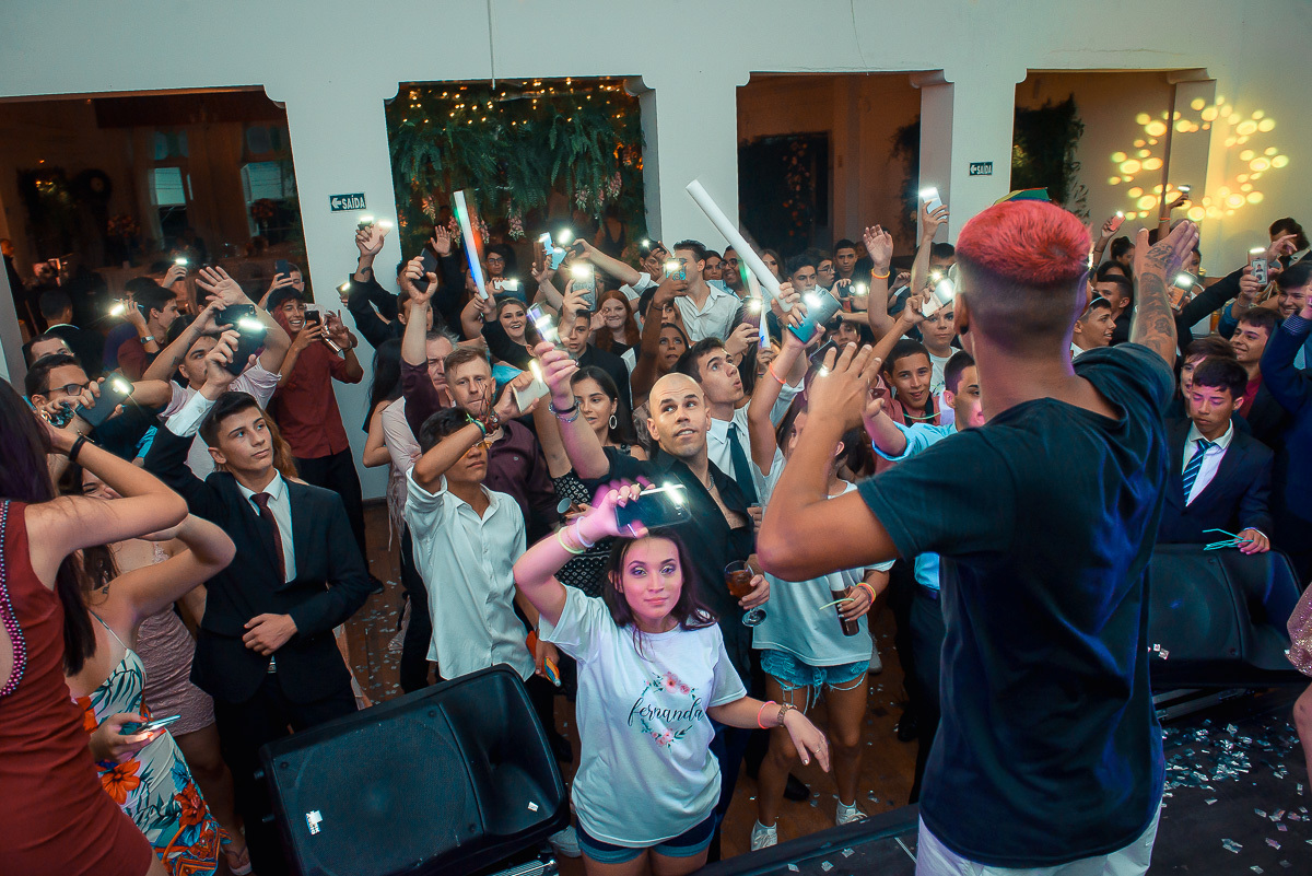 Debutante de braços abertos e muito feliz em cima do palco durante a sua festa de 15 anos em jaguarão.  Foto por Marco Moscarelli fotografo Pelotas.