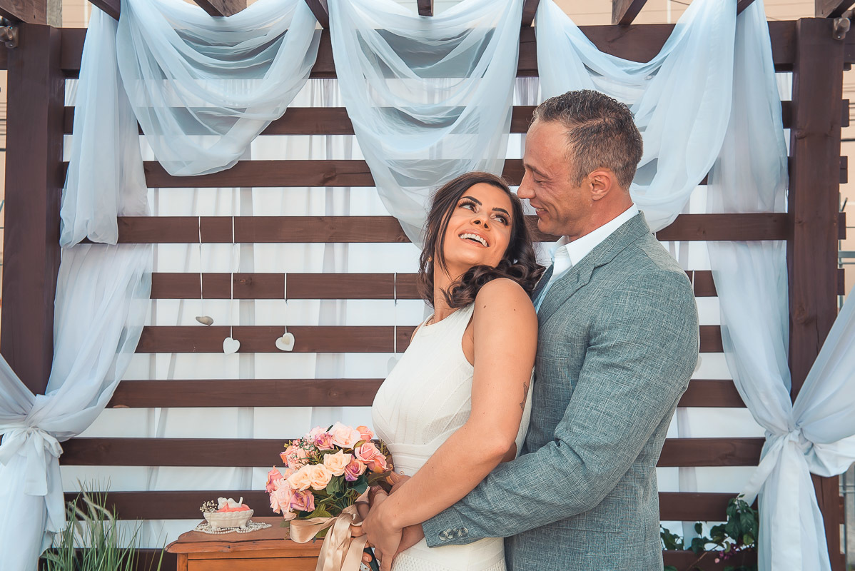 Noiva olhando  sorridente para o noivo durante a cerimõnia de casamento. Retoques finais da maquiagem da noiva momentos antes do casamento. Foto por Marco Moscarelli Fotógrafo Pelotas.