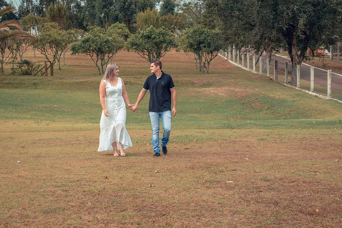 Noivos caminhando alegremente em um campo verde durante o seu ensaio de casal. Noivos trocando um belo beijo durante o seu ensaio de casal. Foto por Marco Moscarelli Fotógrafo Pelotas.