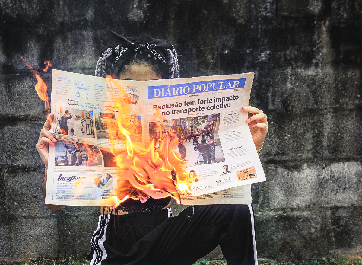 modelo segurando um jornal pegando fogo durante seu ensaio fotográfico Tumblr em Pelotas. Foto por Marco Moscarelli Fotógrafo Pelotas.