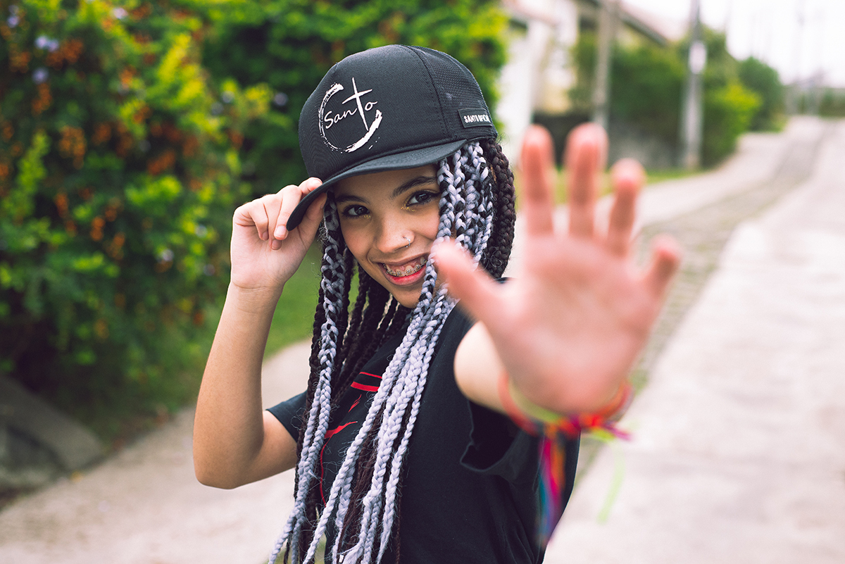 Modelo posando com boné  preto e jeans durante tendo sentada na rua verdes  seu ensaio fotográfico Tumblr em Pelotas. Foto por Marco Moscarelli Fotógrafo Pelotas.