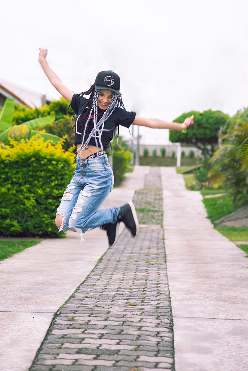 Modelo posando com boné  preto e jeans durante tendo sentada na rua verdes  seu ensaio fotográfico Tumblr em Pelotas. Foto por Marco Moscarelli Fotógrafo Pelotas.