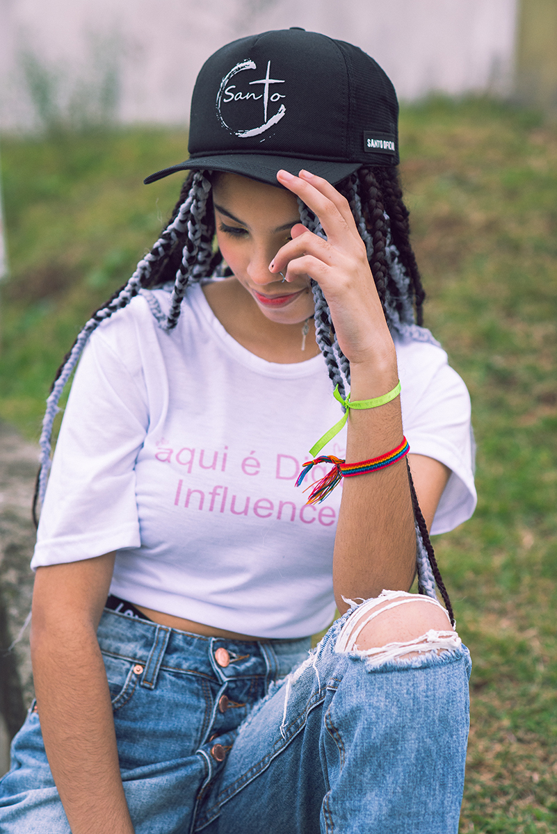 Modelo posando com boné  preto e jeans durante tendo sentada na rua verdes  seu ensaio fotográfico Tumblr em Pelotas. Foto por Marco Moscarelli Fotógrafo Pelotas.