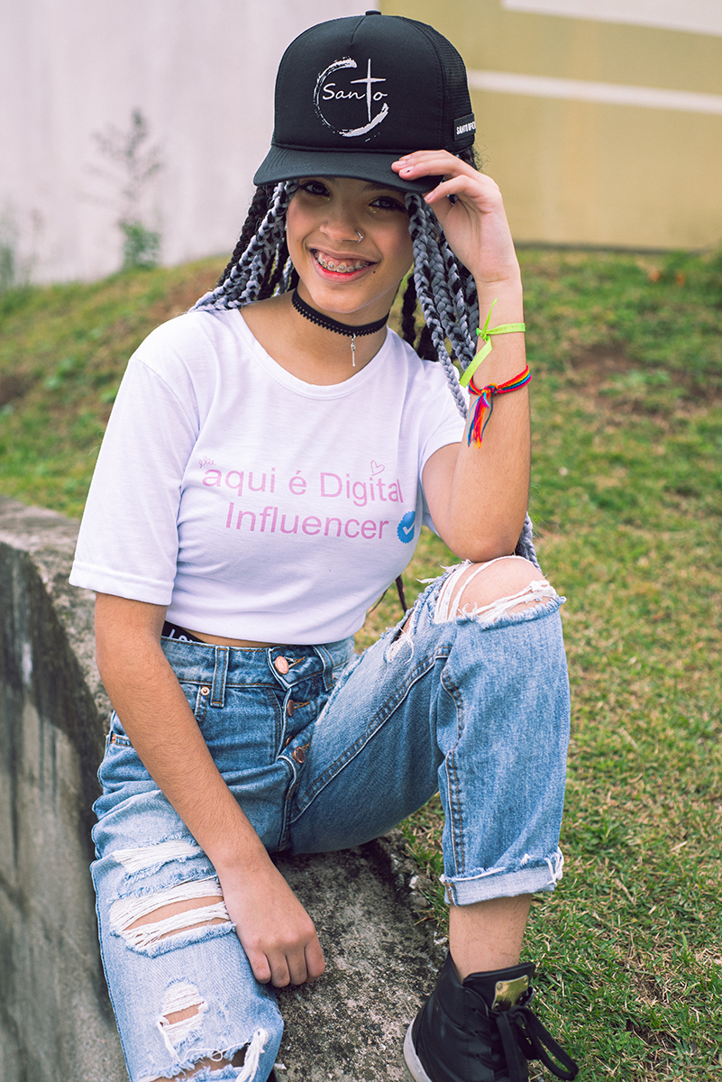 Modelo posando com boné  preto e jeans durante tendo sentada na rua verdes  seu ensaio fotográfico Tumblr em Pelotas. Foto por Marco Moscarelli Fotógrafo Pelotas.