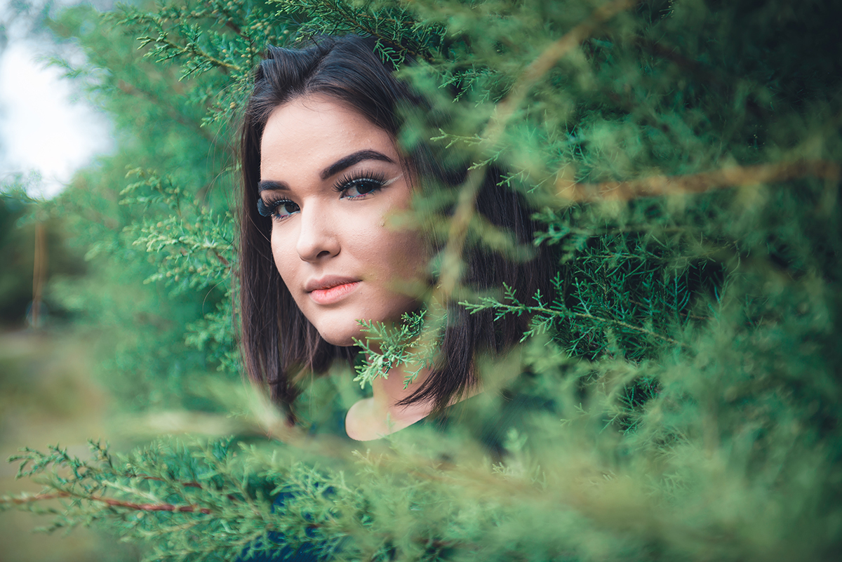 Linda fotografia em detalhe da modelo em meio a folhagens de arvore. Foto por Marco Moscarelli Fotógrafo Pelotas.