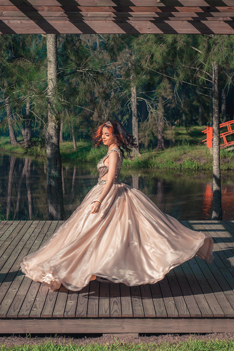 Debutante fotografada enquanto gira com seu vestido de 15 anos durante seu ensaio fotográfico de 15 anos, Debutante caminhando e olhando para trás em um lindo retrato durante seu ensaio fotográfico de 15 anos. Foto por Marco Moscarelli Fotógrafo Pelotas. 