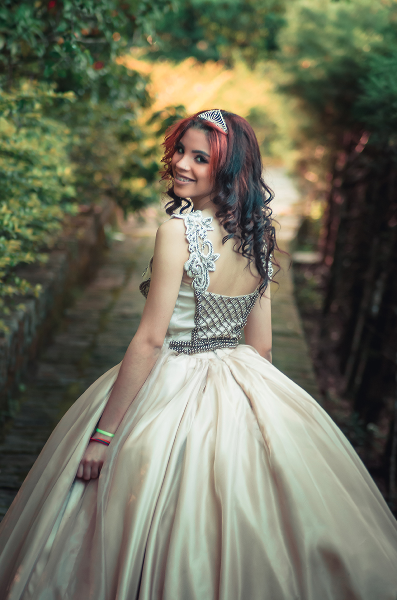 Debutante caminhando e olhando para trás em um lindo retrato durante seu ensaio fotográfico de 15 anos. Foto por Marco Moscarelli Fotógrafo Pelotas.  